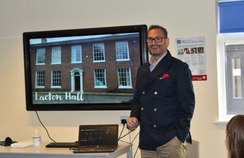 man stood in front of screen picture of lacton hall