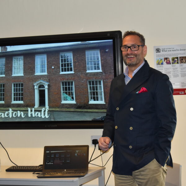 man stood in front of screen picture of lacton hall